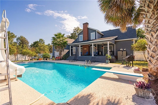 view of swimming pool with a water slide, a diving board, a patio area, and a ceiling fan