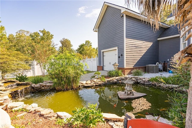 view of side of property with a garden pond, central AC unit, driveway, and brick siding