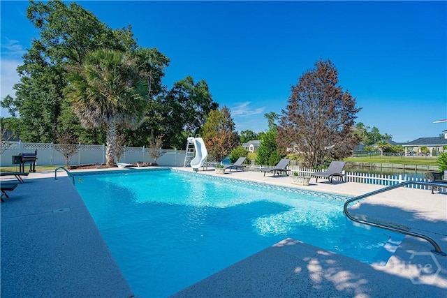 view of swimming pool with a water slide, a patio area, and a diving board