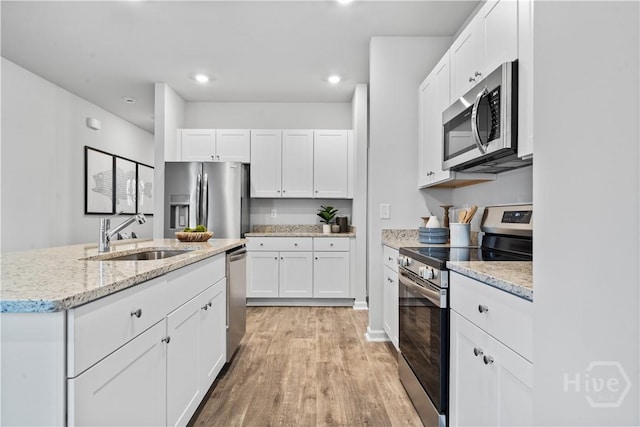 137 Crimson Ln, Savannah, GA 31302 - kitchen featuring appliances with stainless steel finishes, a sink, light wood-style flooring, white cabinets, and light stone counters