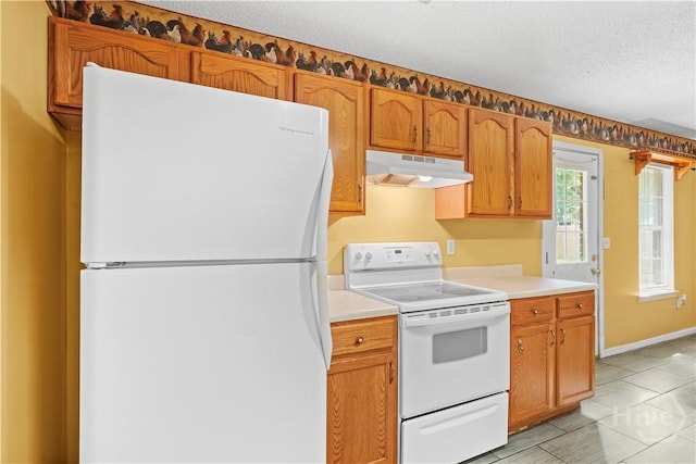 115 Ashley Dr, Guyton, GA 31312 - kitchen featuring white appliances, under cabinet range hood, light countertops, a textured ceiling, and brown cabinets
