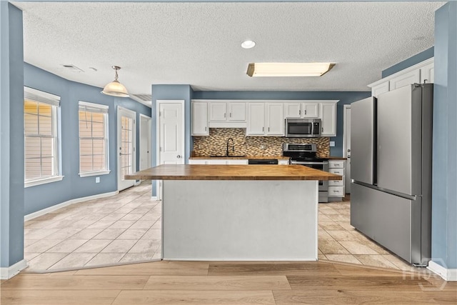 25 Ashley Ct, Richmond Hill, GA 31324 - kitchen featuring appliances with stainless steel finishes, butcher block countertops, white cabinets, a center island, and backsplash