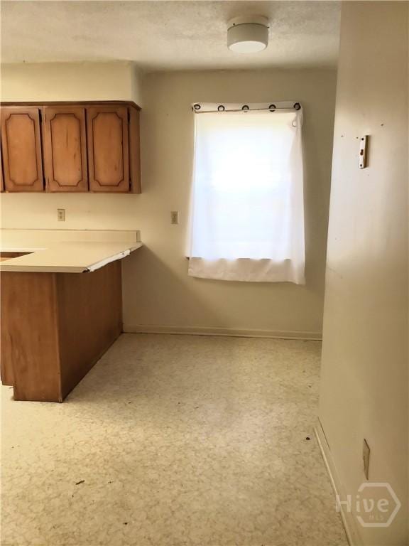 1029 Richards St, Savannah, GA 31415 - kitchen featuring baseboards, brown cabinets, light countertops, and a peninsula
