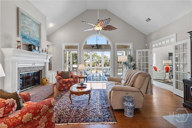 245 Montauk Dr, Richmond Hill, GA 31324 - living room featuring a ceiling fan, wood finished floors, a brick fireplace, high vaulted ceiling, and french doors