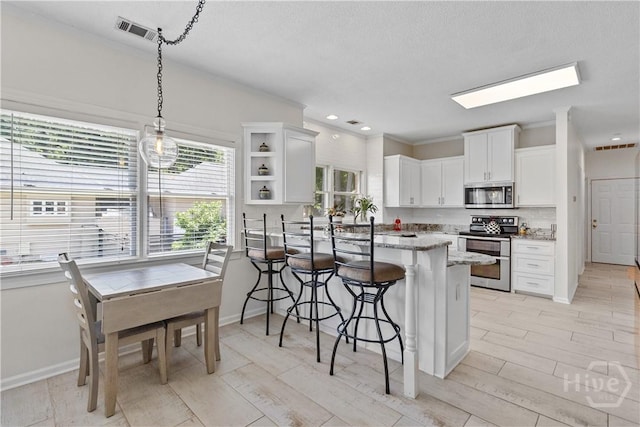 245 Montauk Dr, Richmond Hill, GA 31324 - kitchen with appliances with stainless steel finishes, a breakfast bar area, white cabinetry, light stone counters, and open shelves