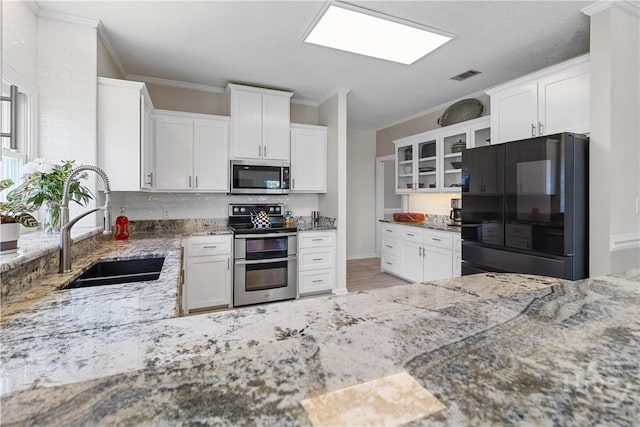 245 Montauk Dr, Richmond Hill, GA 31324 - kitchen with appliances with stainless steel finishes, a sink, ornamental molding, light stone countertops, and glass insert cabinets