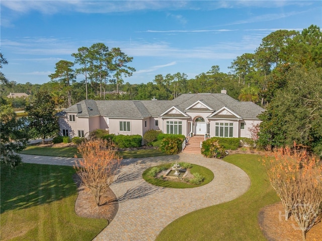 4 Longwater Ln, Savannah, GA 31411 - view of front facade with curved driveway, stucco siding, a front yard, and a chimney