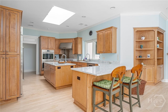 4 Longwater Ln, Savannah, GA 31411 - kitchen featuring a skylight, light wood-type flooring, exhaust hood, a sink, and a peninsula