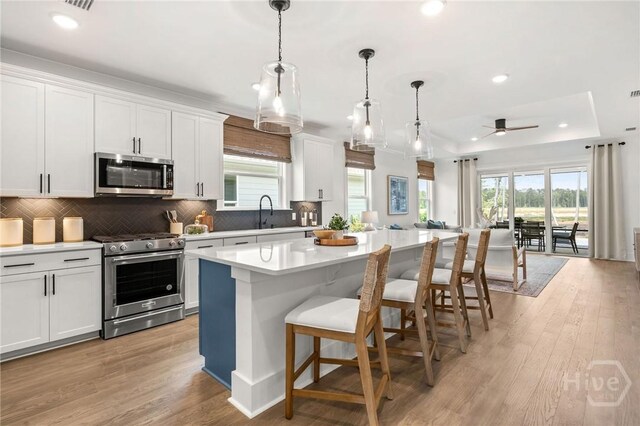 333 Birch Dr, Richmond Hill, GA 31324 - kitchen featuring appliances with stainless steel finishes, ceiling fan, light countertops, decorative backsplash, and a breakfast bar area