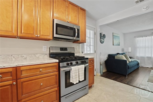 1504 Audubon Dr, Savannah, GA 31415 - kitchen featuring stainless steel appliances, open floor plan, brown cabinets, and light tile patterned flooring