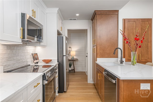 66 Dame Kathryn Dr, Savannah, GA 31411 - kitchen with appliances with stainless steel finishes, a sink, light wood-type flooring, decorative backsplash, and light stone countertops