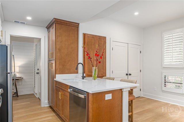 66 Dame Kathryn Dr, Savannah, GA 31411 - kitchen with a sink, appliances with stainless steel finishes, light wood-style floors, a kitchen breakfast bar, and brown cabinets