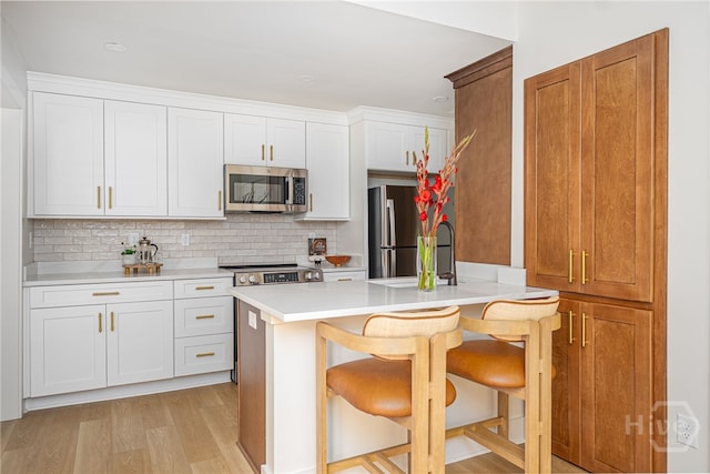 66 Dame Kathryn Dr, Savannah, GA 31411 - kitchen with appliances with stainless steel finishes, a breakfast bar, light countertops, backsplash, and light wood-type flooring