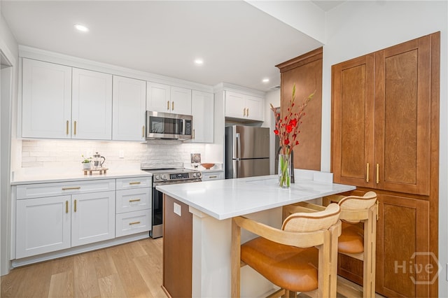 66 Dame Kathryn Dr, Savannah, GA 31411 - kitchen with appliances with stainless steel finishes, a kitchen breakfast bar, light wood finished floors, decorative backsplash, and light countertops