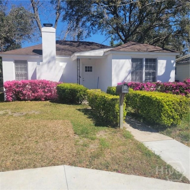 1214 Delesseps Ave, Savannah, GA 31404 - view of property exterior with a lawn, stucco siding, a chimney, and a shingled roof