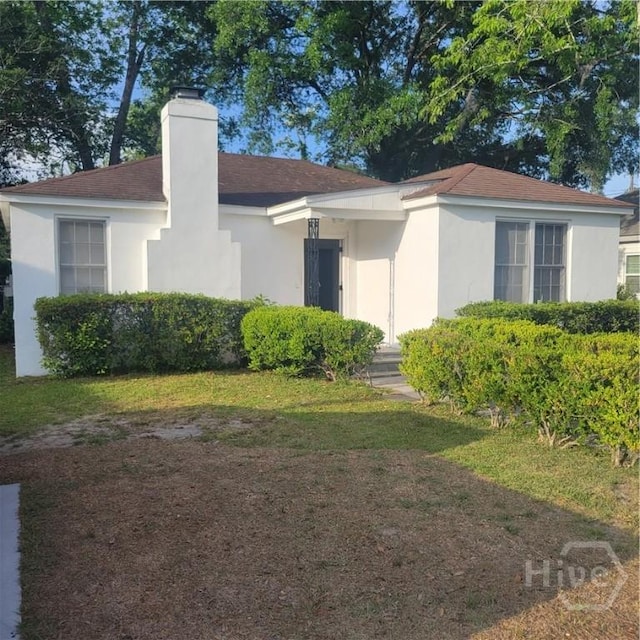 1214 Delesseps Ave, Savannah, GA 31404 - rear view of house featuring a chimney, stucco siding, roof with shingles, and a yard