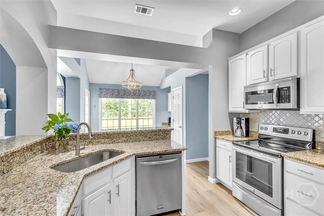 150 Laurenburg Dr, Richmond Hill, GA 31324 - kitchen featuring appliances with stainless steel finishes, a sink, light stone countertops, a chandelier, and white cabinetry