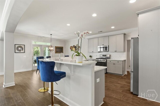 301 Highland Cir, Richmond Hill, GA 31324 - kitchen with appliances with stainless steel finishes, an island with sink, dark wood-style floors, light countertops, and crown molding