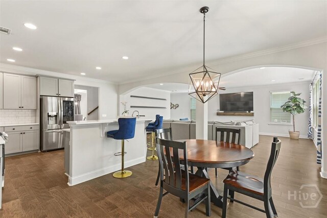 301 Highland Cir, Richmond Hill, GA 31324 - dining space featuring crown molding, a chandelier, dark wood-style floors, recessed lighting, and arched walkways