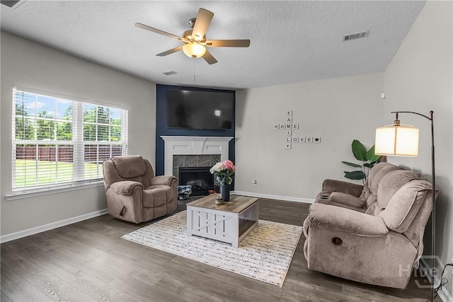 26 Sunflower Cir NE, Ludowici, GA 31316 - living area featuring a textured ceiling, ceiling fan, a tiled fireplace, baseboards, and dark wood finished floors