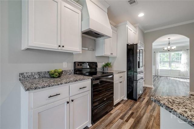 447 Nease Rd, Guyton, GA 31312 - kitchen with black range with electric cooktop, freestanding refrigerator, custom exhaust hood, arched walkways, and wood finished floors