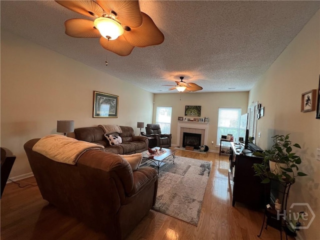 103 Travertine Cir, Savannah, GA 31419 - living room with ceiling fan, a textured ceiling, light wood-style floors, a tiled fireplace, and baseboards