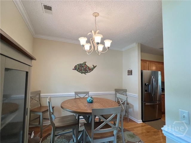 103 Travertine Cir, Savannah, GA 31419 - dining room featuring a textured ceiling, light wood-style floors, a chandelier, and ornamental molding