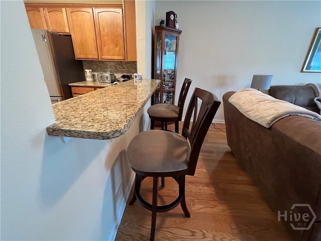 103 Travertine Cir, Savannah, GA 31419 - kitchen featuring freestanding refrigerator, a kitchen breakfast bar, wood finished floors, and baseboards