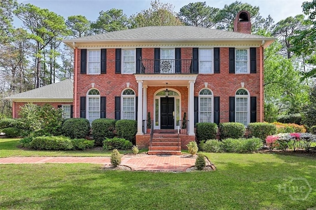 320 Wedgefield Xing, Savannah, GA 31405 - colonial house featuring a balcony, a chimney, a front lawn, and brick siding