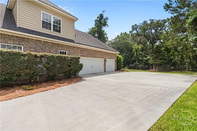 325 Shadow Moss Cir, Richmond Hill, GA 31324 - view of side of home with driveway, brick siding, a garage, and a shingled roof