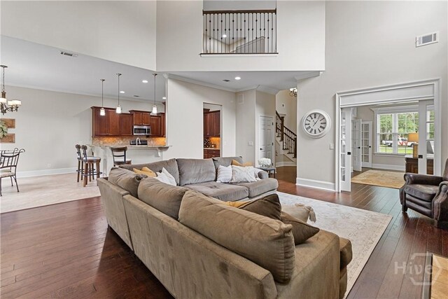 325 Shadow Moss Cir, Richmond Hill, GA 31324 - living area featuring a towering ceiling, stairway, dark wood-style flooring, and a chandelier