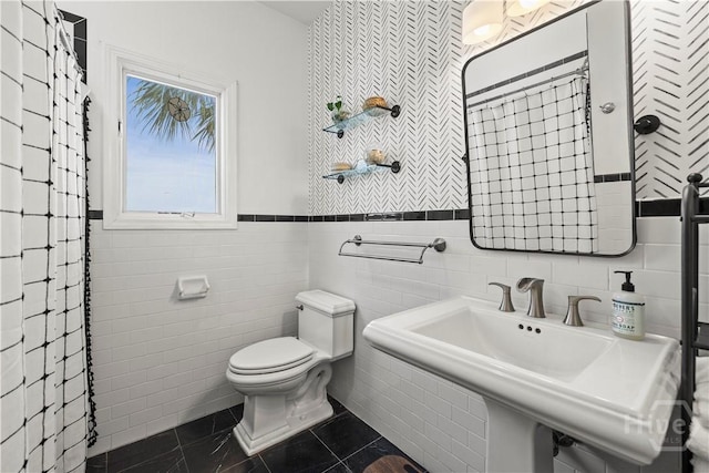 130 Lewis Ave, Tybee Island, GA 31328 - bathroom with tile walls, toilet, a sink, tile patterned floors, and a wainscoted wall
