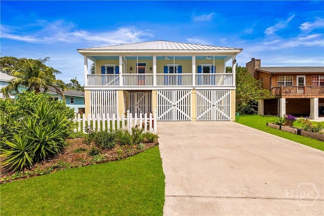 130 Lewis Ave, Tybee Island, GA 31328 - coastal home featuring concrete driveway, covered porch, a front yard, and metal roof