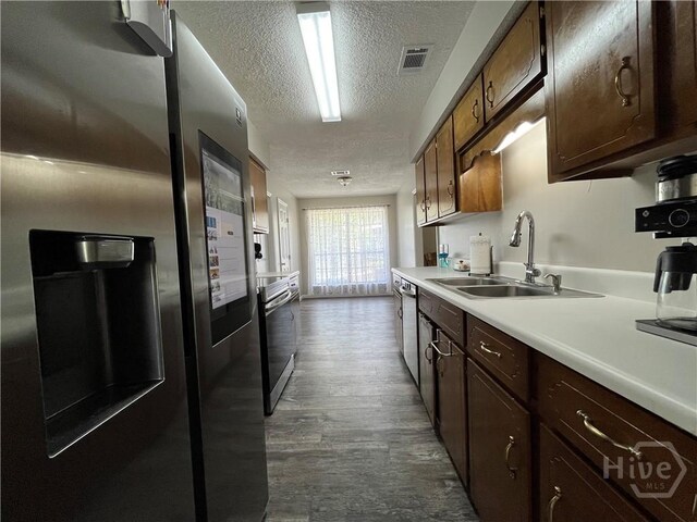 43 Fabian Ln, Hinesville, GA 31313 - kitchen with stainless steel appliances, a textured ceiling, a sink, light countertops, and dark wood-style flooring