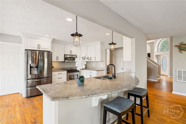108 San Marco Dr, Tybee Island, GA 31328 - kitchen featuring stainless steel appliances, a textured ceiling, a sink, a peninsula, and a breakfast bar
