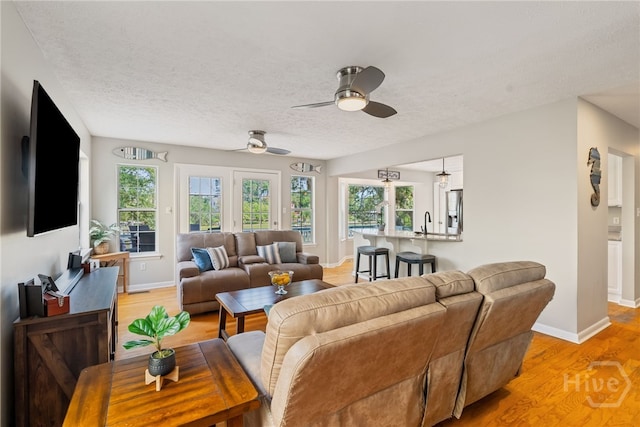 108 San Marco Dr, Tybee Island, GA 31328 - living room featuring light wood-style flooring, baseboards, ceiling fan, plenty of natural light, and a textured ceiling