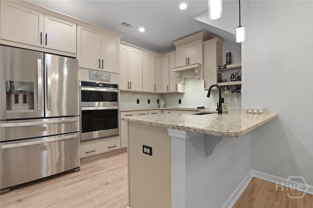 73 Small Pine Ln, Richmond Hill, GA 31324 - kitchen with stainless steel appliances, a sink, a peninsula, light wood-type flooring, and backsplash