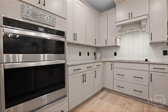 73 Small Pine Ln, Richmond Hill, GA 31324 - kitchen with double oven, decorative backsplash, light wood-style flooring, and light stone countertops
