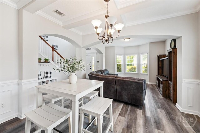 821 NE Mustang Ln, Ludowici, GA 31316 - dining space featuring arched walkways, a chandelier, dark wood-style floors, stairs, and a wainscoted wall