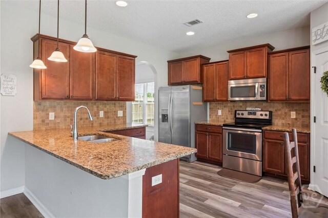 821 NE Mustang Ln, Ludowici, GA 31316 - kitchen featuring stainless steel appliances, a sink, light stone counters, a peninsula, and arched walkways