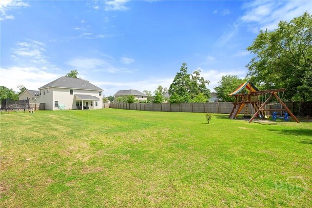 821 NE Mustang Ln, Ludowici, GA 31316 - fenced backyard with a trampoline and a playground
