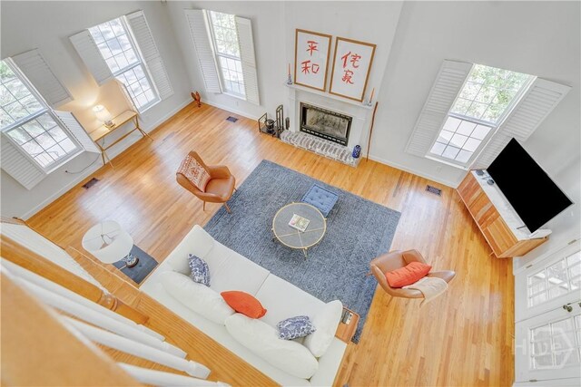 8720 Ferguson Ave, Savannah, GA 31406 - living area featuring a fireplace with raised hearth, wood finished floors, a high ceiling, and baseboards
