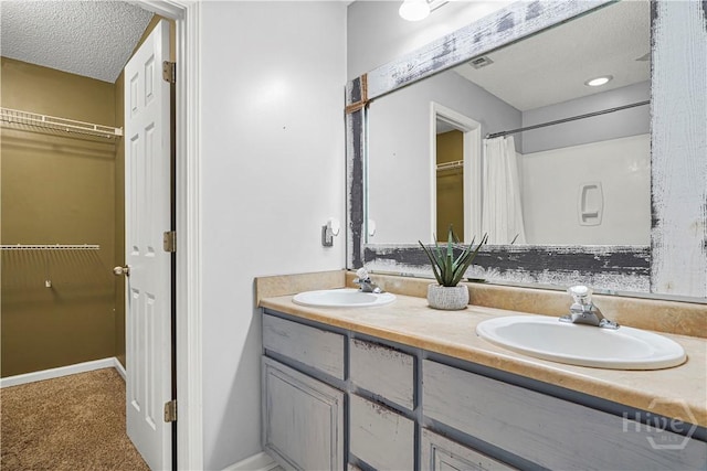 125 Crossing Cir, Rincon, GA 31326 - bathroom with double vanity, a walk in closet, a textured ceiling, baseboards, and a shower with curtain