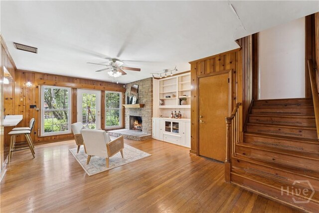 1525 Whitney Rd, Savannah, GA 31406 - living area with ceiling fan, a large fireplace, wood finished floors, stairs, and wood walls