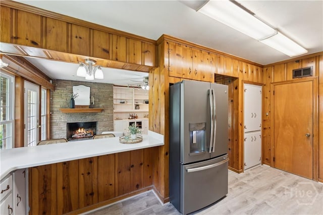 1525 Whitney Rd, Savannah, GA 31406 - kitchen featuring stainless steel fridge with ice dispenser, light wood-type flooring, a fireplace, light countertops, and wood walls