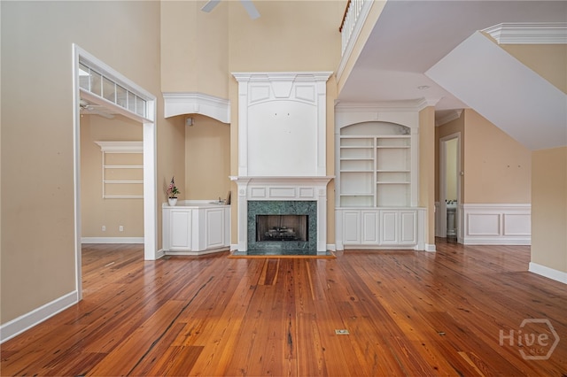 2 Franklin Creek Rd S, Savannah, GA 31411 - unfurnished living room with ceiling fan, hardwood / wood-style flooring, built in shelves, a premium fireplace, and a high ceiling