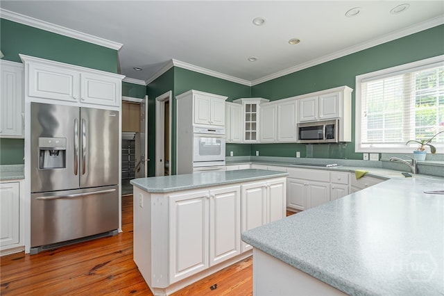 2 Franklin Creek Rd S, Savannah, GA 31411 - kitchen with stainless steel appliances, light wood finished floors, ornamental molding, white cabinets, and a center island