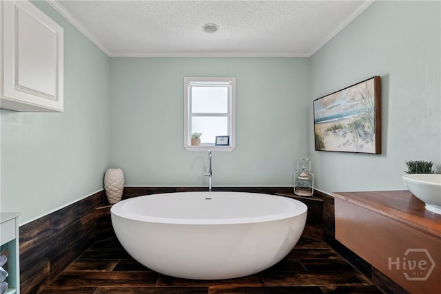 1406 Jones Ave, Tybee Island, GA 31328 - full bathroom featuring a freestanding bath, vanity, a textured ceiling, crown molding, and wood finished floors