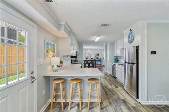 1406 Jones Ave, Tybee Island, GA 31328 - kitchen featuring appliances with stainless steel finishes, a peninsula, light countertops, dark wood-style floors, and a textured ceiling