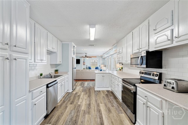 1406 Jones Ave, Tybee Island, GA 31328 - kitchen with appliances with stainless steel finishes, light wood-type flooring, white cabinetry, light countertops, and a textured ceiling